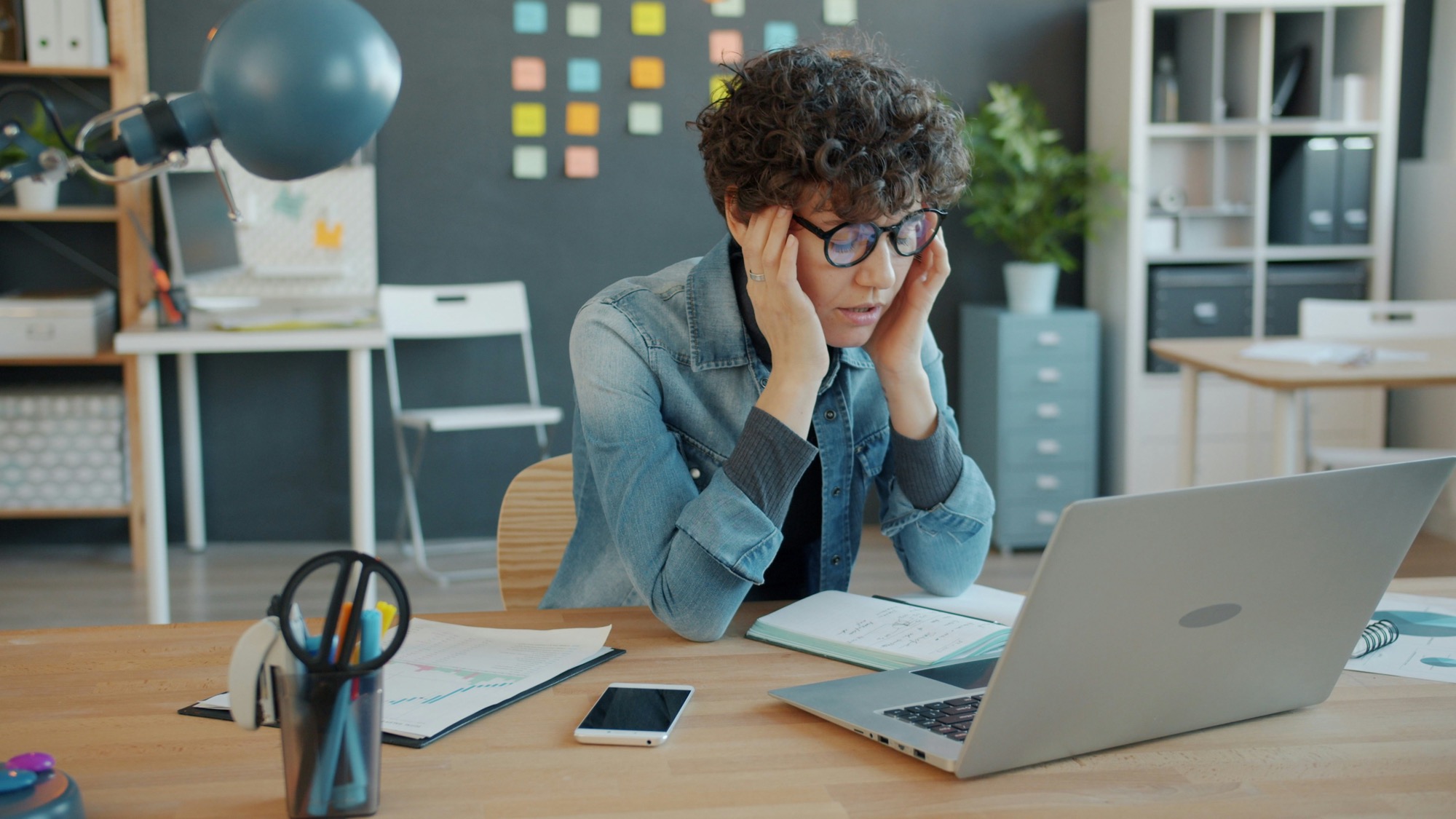 Tired employee holding their head while working on a laptop